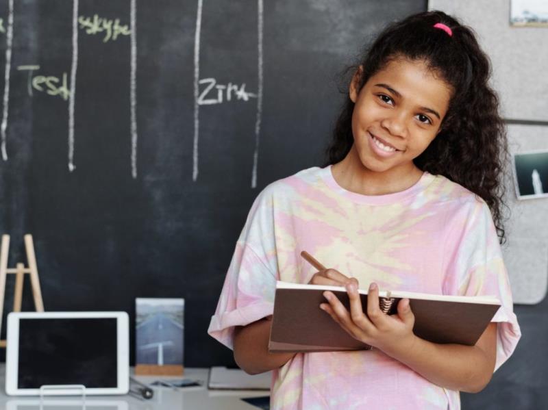 latina girl standing in front of blackboard smiling